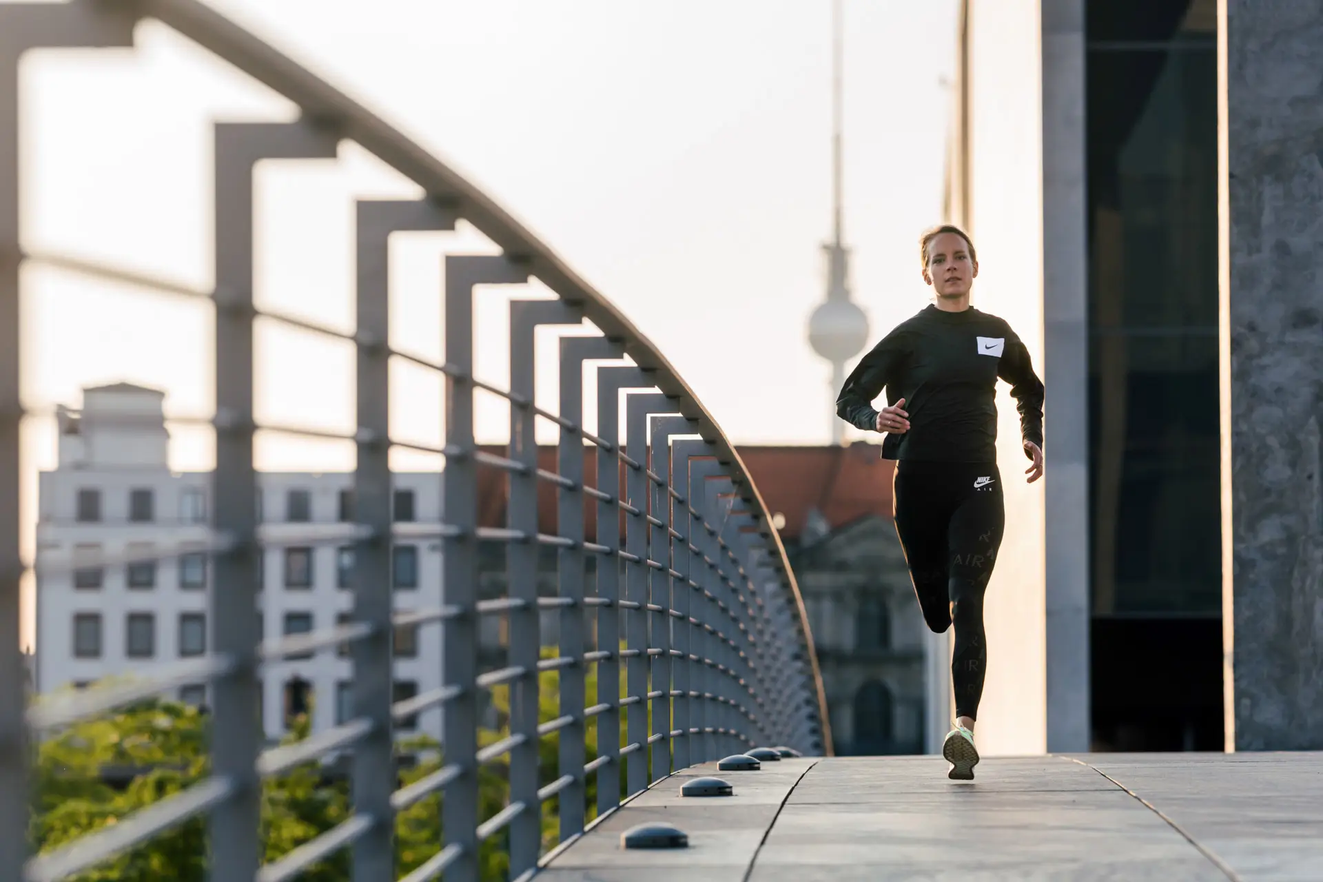Läuferin auf Brücke vor Stadtarchitektur – Kampagnenfoto Leipzig von Carsten Beier